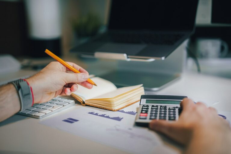 Person working out costs with a calculator and notebook